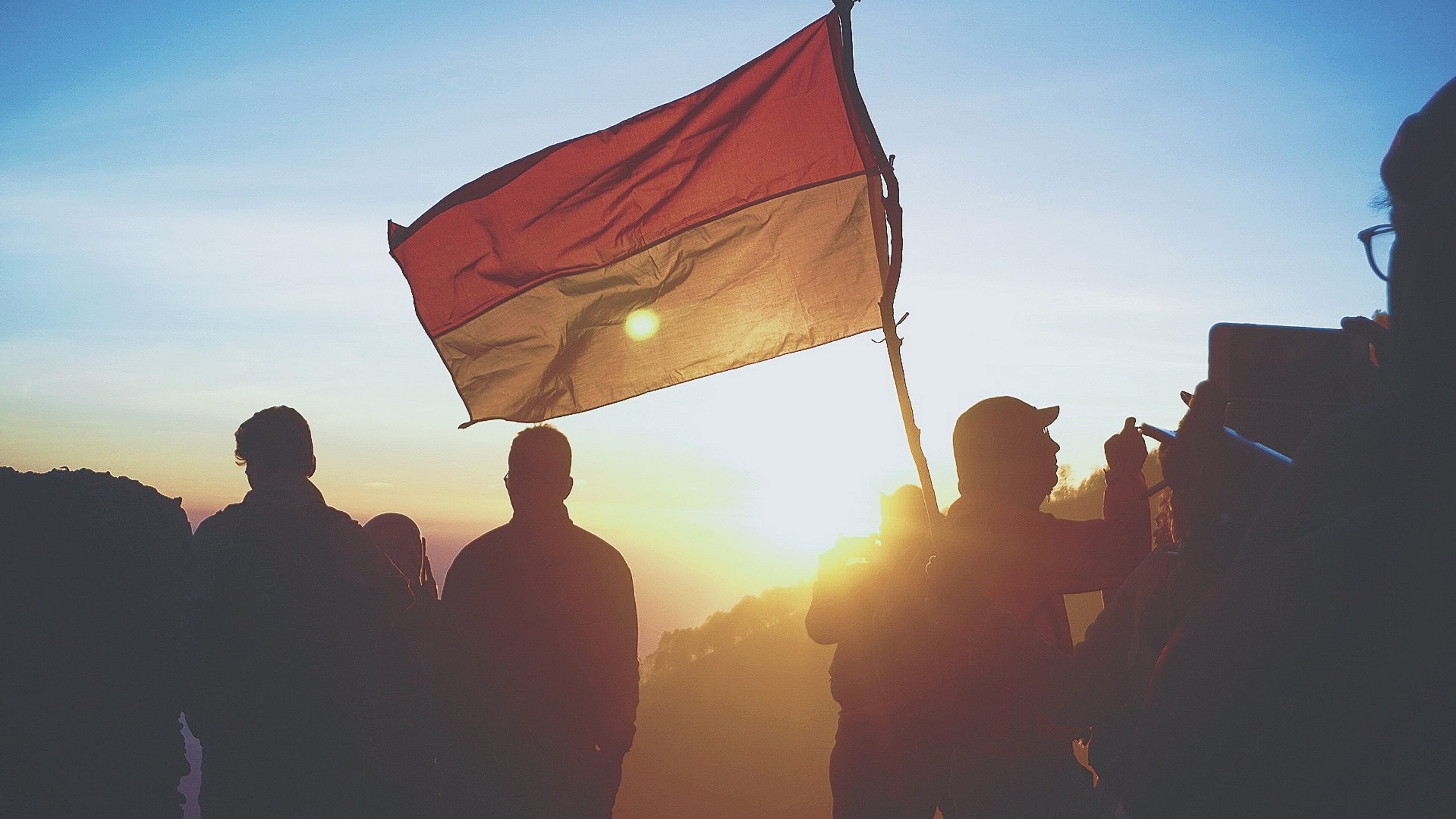 silhouette of people holding red and yellow flag