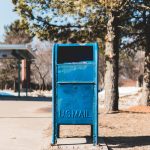 blue U.S. mail box on concrete pavement