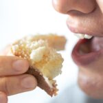 A woman eats bread with grated cheese, close-up, breakfast concept.