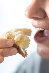 A woman eats bread with grated cheese, close-up, breakfast concept.