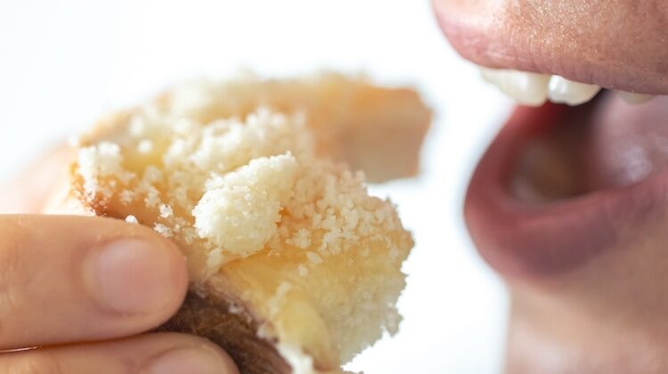 A woman eats bread with grated cheese, close-up, breakfast concept.