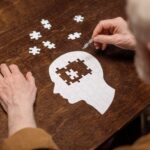 high angle view of senior man collecting jigsaw puzzle as dementia rehab