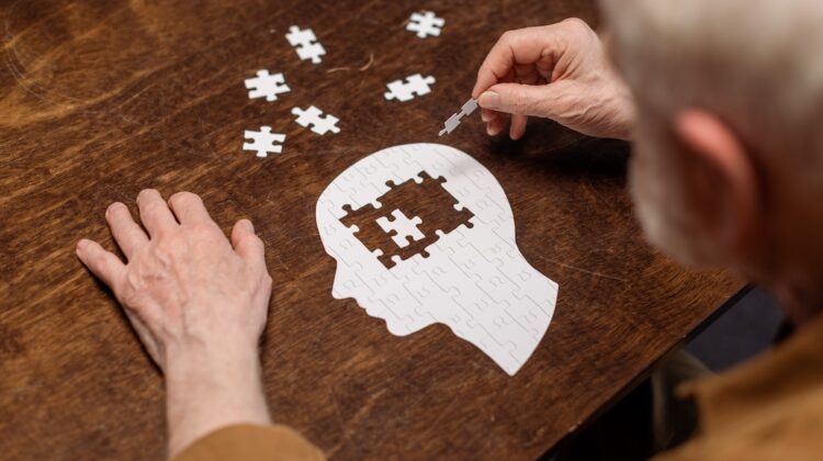 high angle view of senior man collecting jigsaw puzzle as dementia rehab